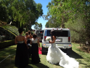 Bride with bridesmaids walking to white hummer limo