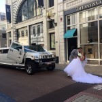 Bride and groom kissing in front of a brand new custom Hummer wedding limo