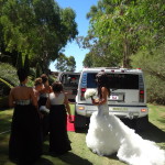 Bride with bridesmaids walking to white hummer limo